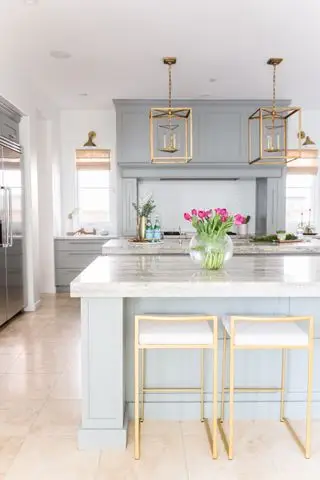 cuisine bleue avec 2 îlots de cuisine, tabourets dorés et lanternes suspendues, sol en pierre