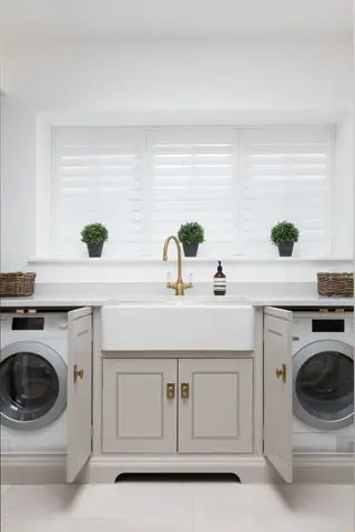 Une buanderie intelligente avec des placards gris et des finitions en laiton.
