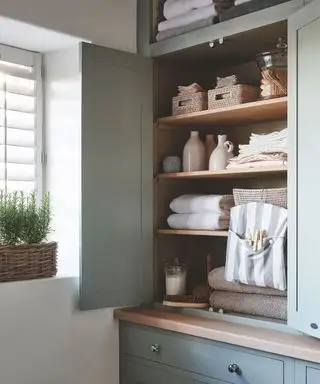 Idées de buanderie pour le rangement avec une armoire en bois organisée remplie de linge.