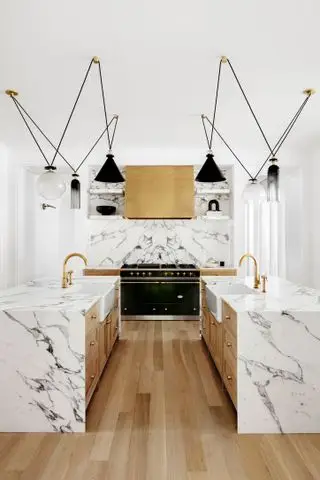 cuisine avec surfaces en marbre et îlots doubles avec éviers Belfast assortis avec éclairage suspendu contemporain au-dessus et cuisinière