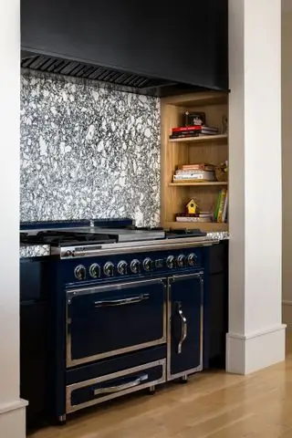 Poêle avec dosseret en pierre veinée et niche avec livres de recettes