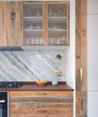 대리석 백스플래시와 천연 목재 캐비닛을 갖춘 주방