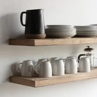 Tasses et petites cruches alignées dans la même direction sur une étagère flottante en bois