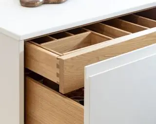 Armoires de cuisine blanches montrant un tiroir qui s'ouvre sur une unité de base blanche avec une section de rangement coulissante cachée pour les couverts