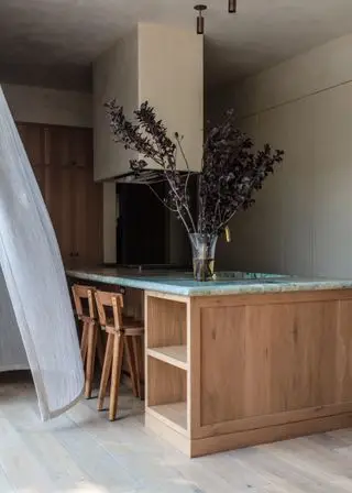 Comptoir d'îlot de cuisine en marbre vert et blanc, chaises hautes en bois