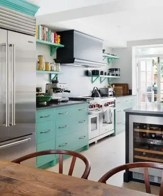 ステンレス製のレンジと冷蔵庫を備えたアクアキッチン、ワイン冷蔵庫と木製のテーブルと椅子を備えたアイランド