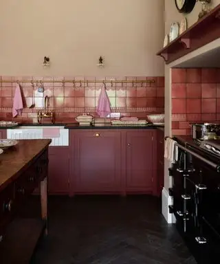 šejkrové kuchyně, červená a světle šedá kuchyně s dlážděným pozadím, mosazná závěsná tyč, police, vintage stůl