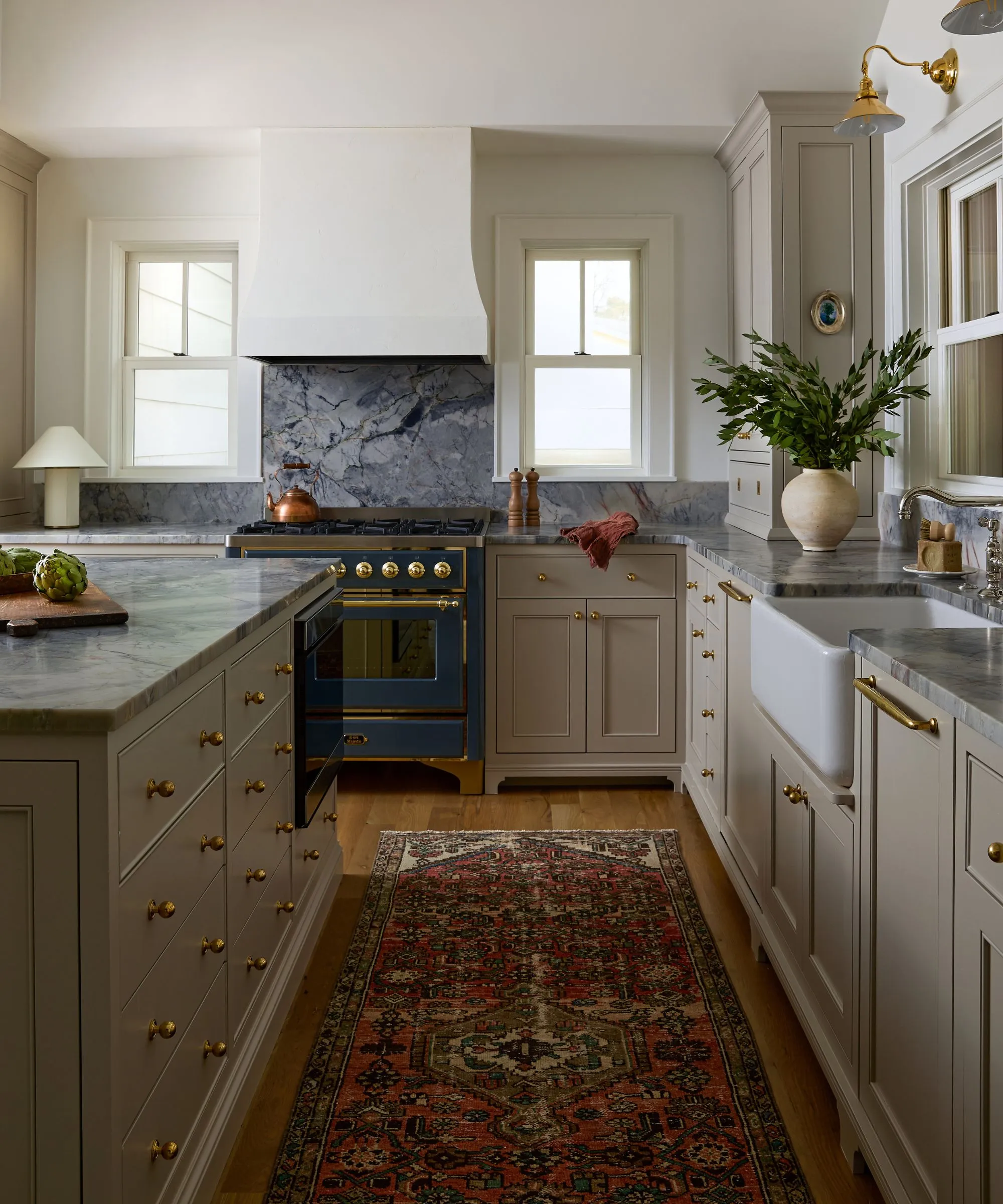 호숫가 전망이 보이는 대형 창문이 있는 소박하고 중립적인 주방, 대형 석고 밥솥 후드와 파란색 대리석 조리대' loading='lazy' title=