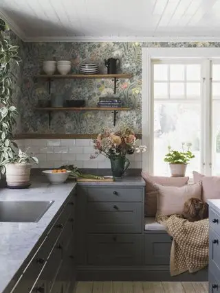 papier peint vert clair dans une cuisine de style scandinave avec des armoires gris foncé, un siège de fenêtre et un chien