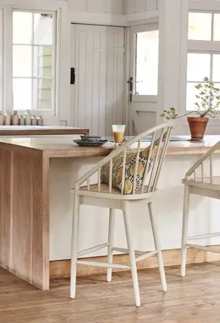 cuisine avec parquet et tabouret de bar haut près d'un îlot en bois et blanc