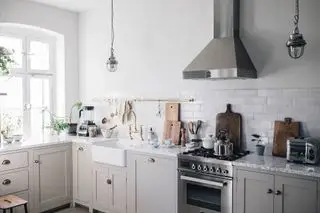 Cuisine Scandi avec armoires gris pâle et murs blancs ainsi que des accessoires chromés