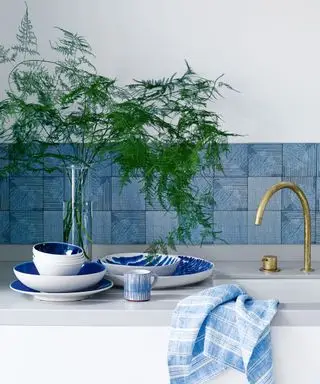 Beispiel für die Installation eines Backsplash mit blauen Fliesen und dunklem Fugenmörtel in einer weißen Küche.