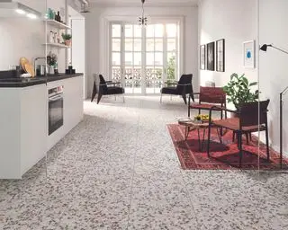 Une cuisine-salle à manger blanche avec un carrelage en terrazzo gris démontrant des idées de revêtement de sol de cuisine contemporaines.