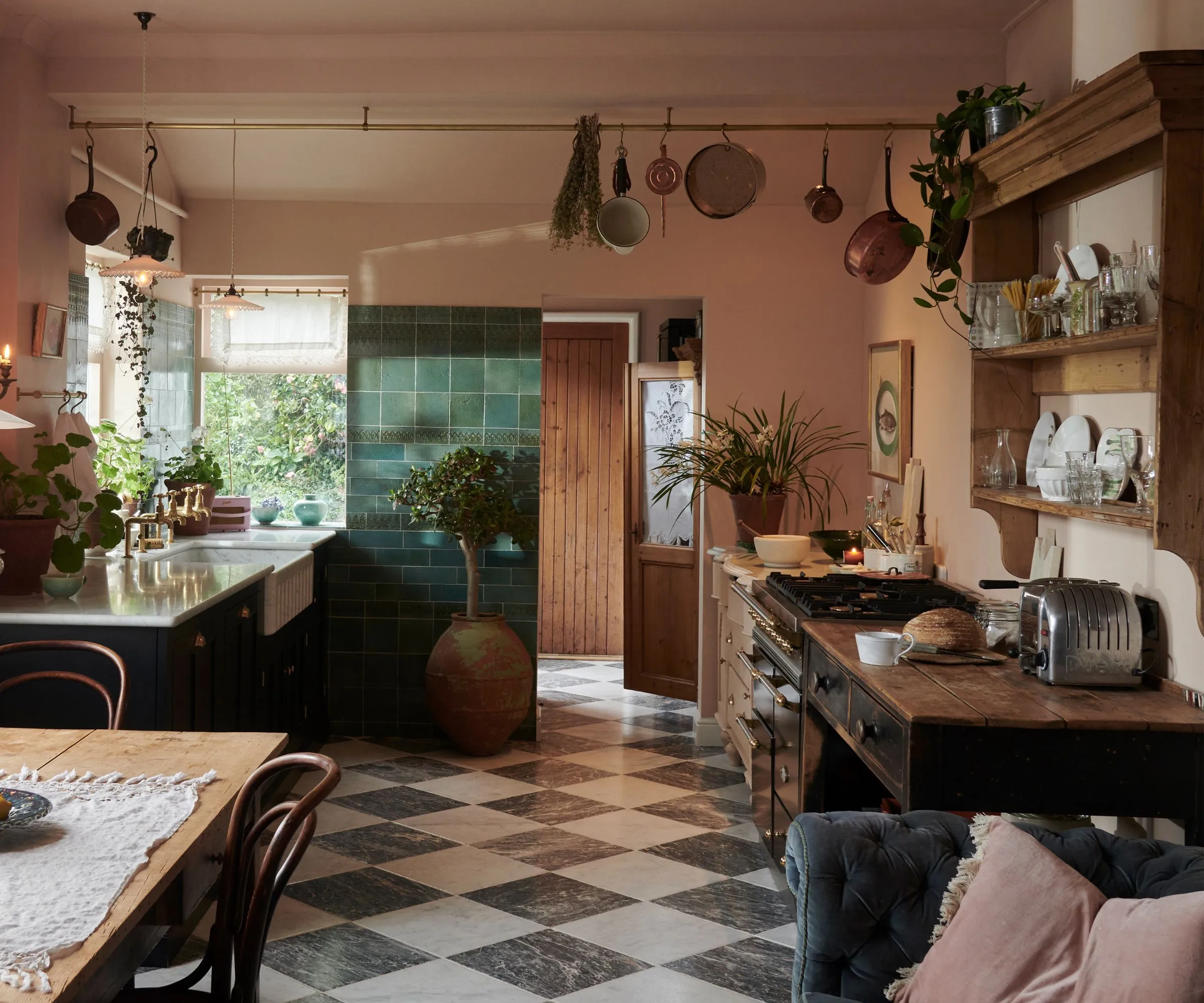 테이퍼 양초를 겹겹이 쌓은 직물과 예쁜 도자기를 전시할 수 있는 개방형 선반으로 겨울을 장식한 아늑한 녹색 및 분홍색 주방' loading='lazy' title=