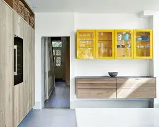 Grande cuisine avec murs blancs, armoires en bois et armoires peintes en jaune