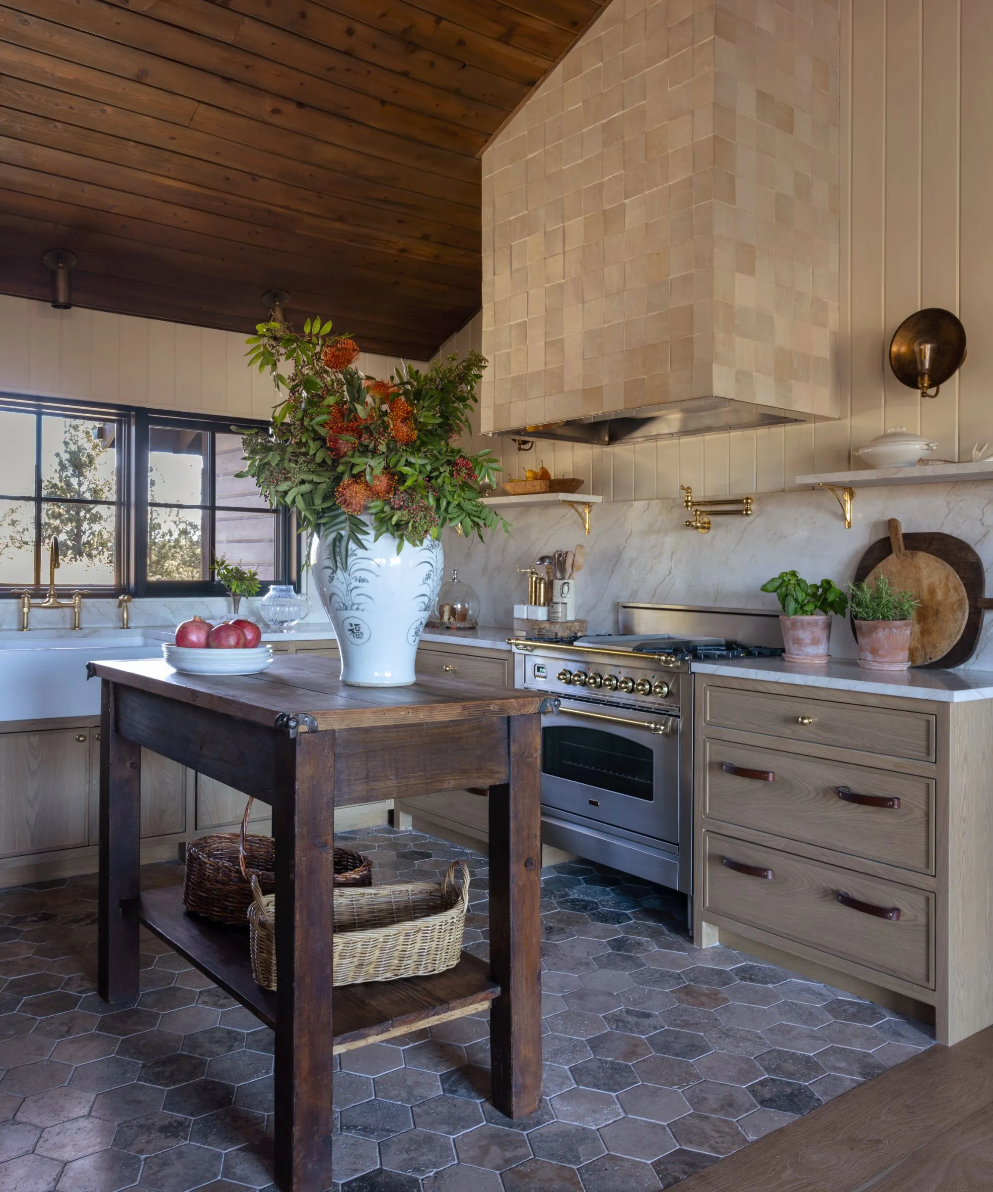 Teplá rustikální kuchyně s dřevěnými skříňkami, mramorovým pozadím a texturovanými čtvercovými dlaždicemi pokrývajícími varnou desku sporáku' loading='lazy' title=