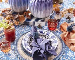 Ideias centrais para o Dia de Ação de Graças com toalha de mesa estampada em azul e branco, folhas de outono e decorações de abóbora azul