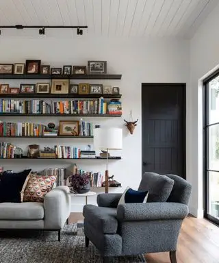 obývacia izba so sivou pohovkou a stoličkou s policami na bielych stenách