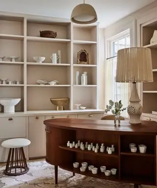 Mesa de madeira, prateleiras e paredes cor de pêssego, banco branco