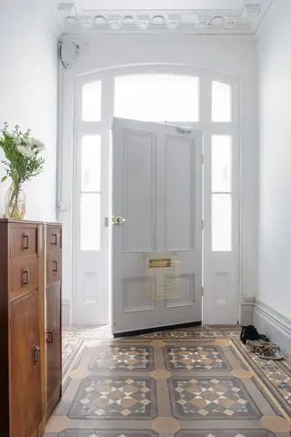 白い廊下の壁、タイル張りの床、木製キャビネット