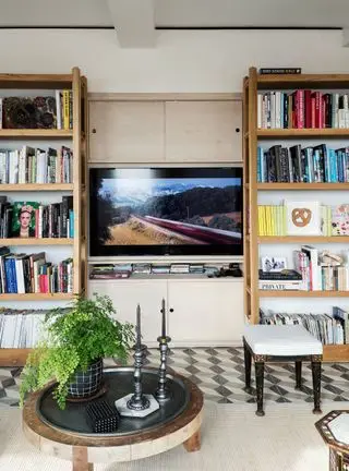 Televizní místnost s knihovnou postavenou kolem centrální televize na krémové stěně