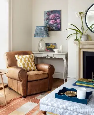 כורסת עור חומה עם כרית צהובה, מנורה כחולה והעות'מאנית כחולה.