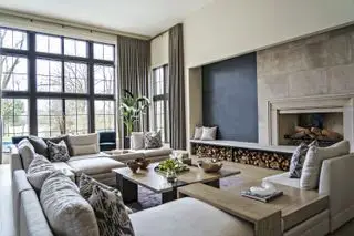 大きな断面、丸太の山、コーヒーテーブル、カーテン、黒い重要な窓、石造りの暖炉を備えたニュートラルなリビング ルーム