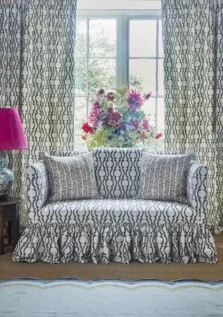 sofá y cortinas a juego, estampado festoneado gráfico negro, volantes en el sofá, flores, lámpara de mesa con pantalla rosa, alfombra con bordes festoneados