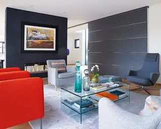 Un esquema de sala de estar de apartamento en azul oscuro, blanco y rojo con sillones uno frente al otro alrededor de una mesa de centro de acrílico.