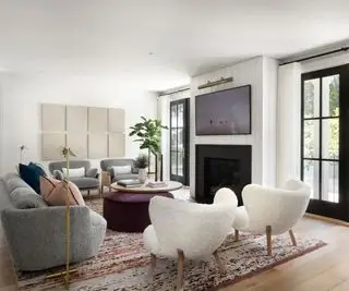 סלון עם שני שולחנות קפה עגולים קירות לבנים יצירות אמנות ורצפות עץ עם שטיח