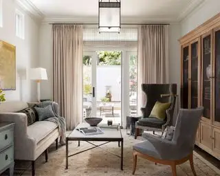 Una sala de estar estrecha con muebles neutros y paleta de colores.