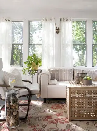 salón con muebles tradicionales, alfombra antigua y cortinas transparentes