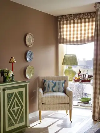 In Ocker gestrichenes Wohnzimmer mit gemustertem Sessel und karierten Jalousien.