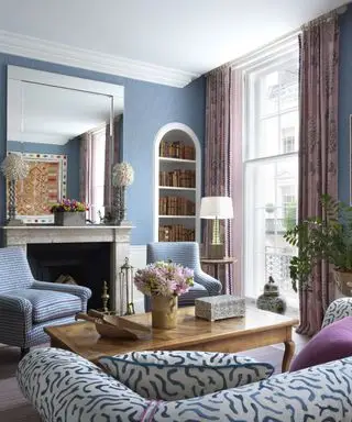 Pomysły na formalny salon z niebieskimi ścianami, wbudowanym w łuk regałem, różowymi zasłonami i niebiesko-białymi siedzeniami
