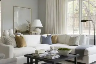 Cremefarbenes Wohnzimmer mit weißem Sofa und übergroßer Kunst an der Wand