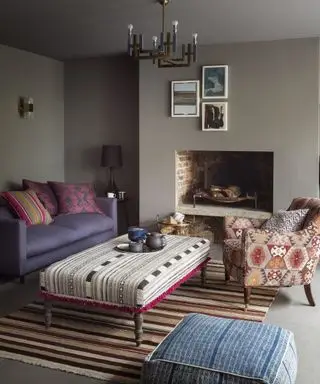 줄무늬 덮개를 씌운 오토만, 줄무늬 러그, 무늬가 있는 안락의자가 있는 아늑한 회색 거실