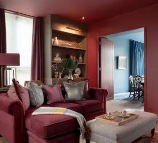 Rød stue med rød sofa, røde vægge og dør og trægulv