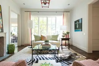 Neutral stue med rødmønstret polstring, gardinbeklædning og vaser