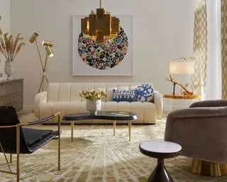 Jonathan Adler mostra como planejar a iluminação da sala de estar, com sofá creme e luminária pendente dourada.