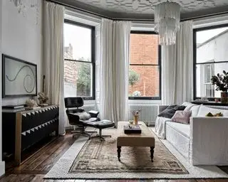 Weißes, modernes Wohnzimmer mit weißem Sofa, Fernseher und gemustertem Teppich