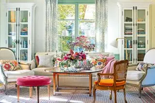 Schönes Wohnzimmer mit Sofa und Sesseln und elegantem Blumenarrangement auf dem Couchtisch in der Mitte