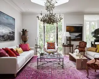 En lysekrone i et storslået design med rødt orientalsk tæppe, der demonstrerer små stuebelysningsideer.