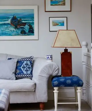 En bordlampe, der viser små stuebelysningsideer ved siden af ​​en bleg sofa med blåt tilbehør.