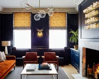 Pendel i glas, en væglampe og en bordlampe mod mørkelilla vægge som eksempler på små stuebelysningsideer.