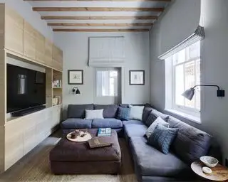 Lille stuebelysningsideer med sorte væglamper over en stor L-formet blå sofa.