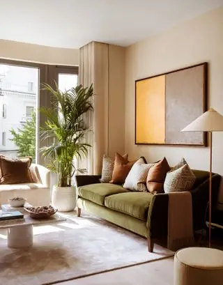 neutral stue med grøn sofa, rust og mønstrede hynder, maleri på væg, maling, gulvlampe, gardiner