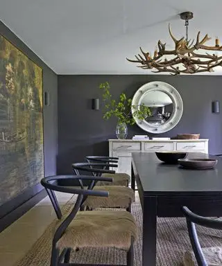 salle à manger avec murs gris foncé, lustre en bois de cerf, table et chaises noires