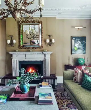 סלון ניטרלי בסגנון מסורתי עם קירות בז', אח, נברשת וספה ירוקה