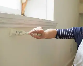 브러시로 창문 주변의 벽을 손으로 칠하기