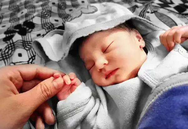 Newborn baby with inspirational name sleeping in gender neutral clothing